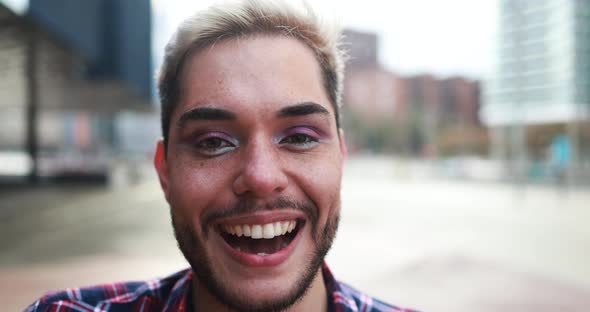 Young transgender man with makeup smiling on camera outdoor