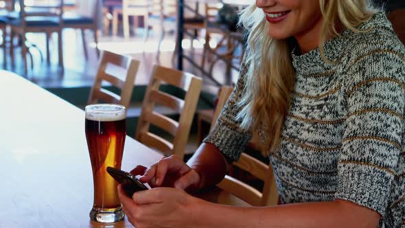 Beautiful woman using mobile phone at bar counter 4k