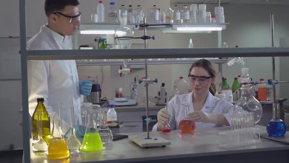 Chemist Engineer Holding Flasks Adding Liquid To Test-tubes With alt
