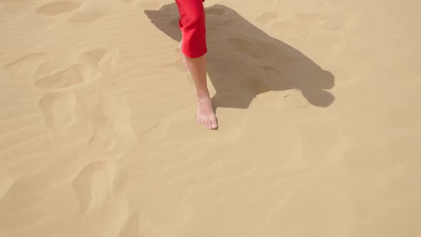 Sexy Brunette Woman in a Red Satin Long Dress Walks on Sand Dunes in the Desert