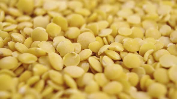 Uncooked yellow lentils fall into a heap in slow motion