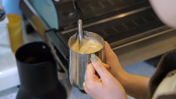 Female Barista Steaming Milk for Coffee Order