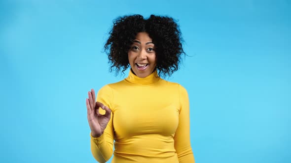 African Woman Showing Ok Sign Over Blue Studio Background