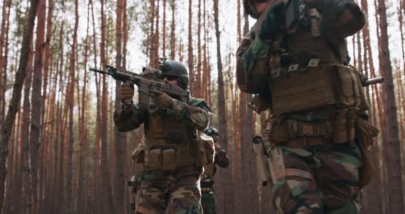 Squad of Four Fully Equipped Soldiers in Camouflage on a Reconnaissance Military Mission Aiming