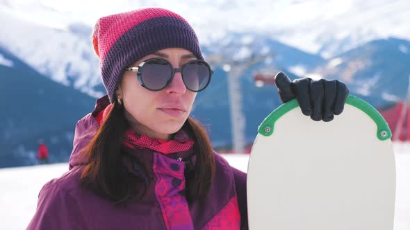 A Young Woman on a Snowboard on Top Mountain on a Ski Track