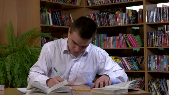 Male Student Researching with a Book in a Library