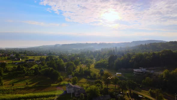 Aerial view over homes and countryside nature, in the Carpathian Mountains, misty, summer day, in ru