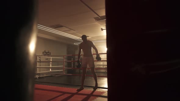 Kickboxing, the Athletic Man Fighter Stands Near the Boxing Ring After Training, Training Day in the