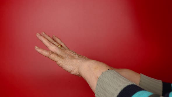 Elderly Woman's Hands on Red Background