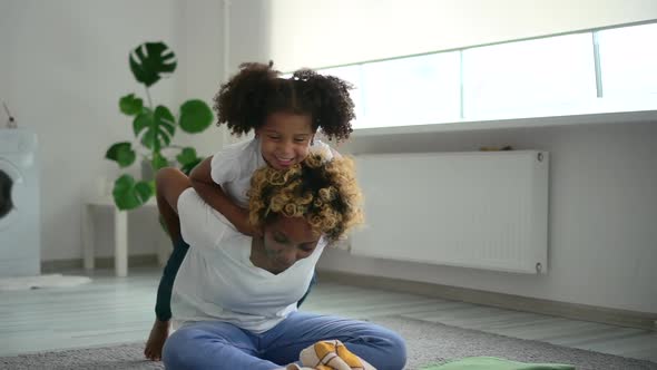 Young Mother and Cute Daughter Have Fun and Sit on Floor in Laundry Room Spbd