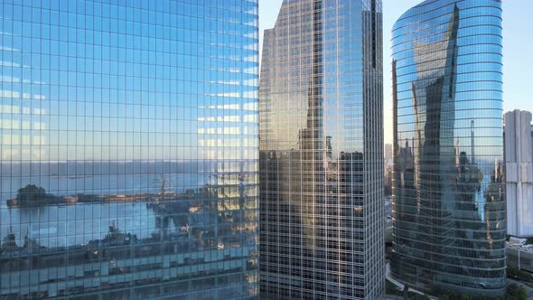 Aerial dolly in of Puerto Madero piers mirrored in window glass skyscrapers at golden hour, Buenos A