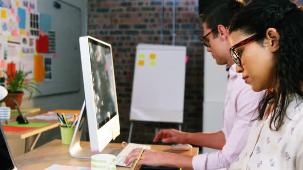 Businesswoman sitting with coworker while working on computer