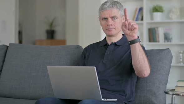 Focused Middle Aged Businessman with Laptop Pointing with Finger