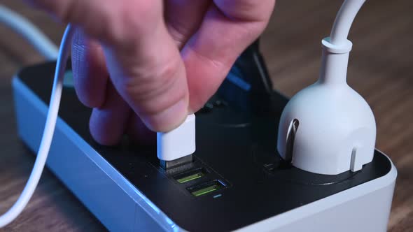 Closeup of a Male Hand Plugging Cables Into a Power Outlet