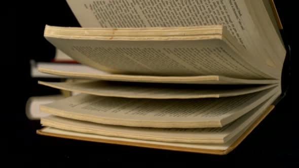 Old book falling on black background, Slow Motion alt