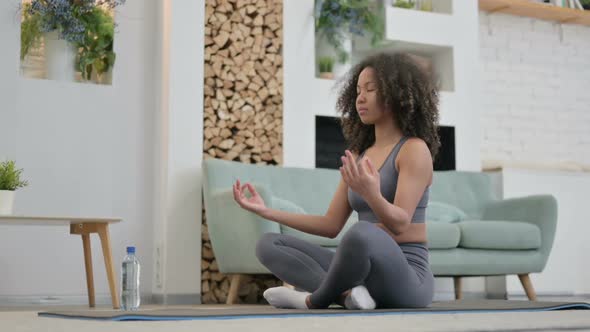 Young African Woman Doing Meditation on Yoga Mat at Home