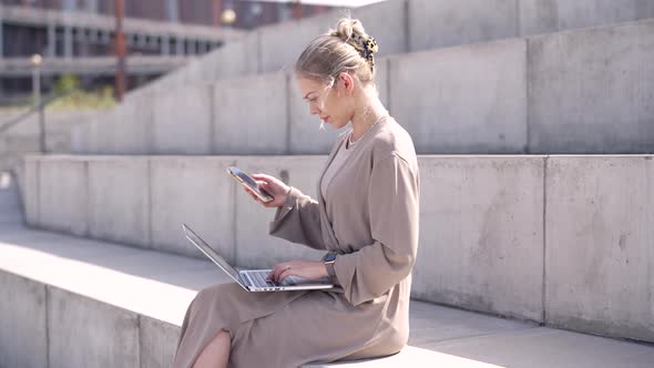 Young Female Using Devices on Street