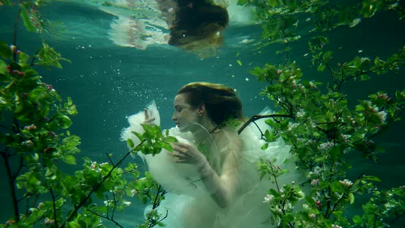 Beautiful Pretty Woman in White Gown is Swimming in Fabulous Underwater Garden Slow Motion Shot