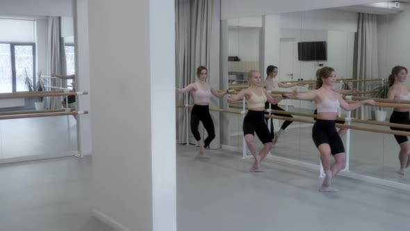 Ballerinas warm up in the studio in front of a mirror in a white bright dance hall, warm-up