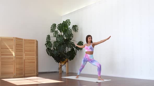 Attractive woman wearing sport bra practice yoga in light room. Female do stretching.