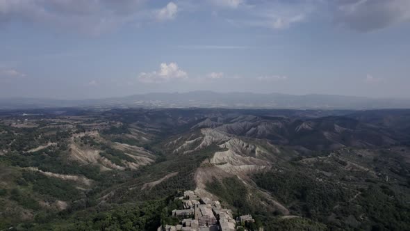 -PLANE: from crane back to bird's eye view-DESCRIPTION: video with drone over the civita di Bagnore