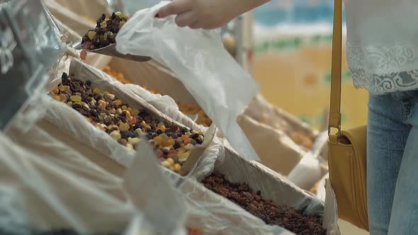 Young Girl Pours Dried Fruit Into a Package