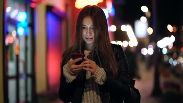 Woman Standing at The Street at The Evening Time with Mobile Phone
