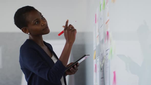 African american businesswoman thinking and making notes on whiteboard