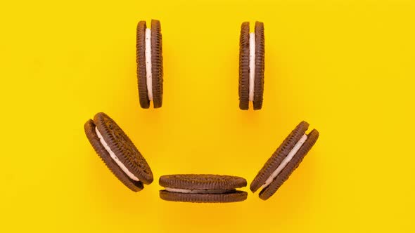 Sweet brown cookies with white cream inside move on yellow background. Stop motion animation