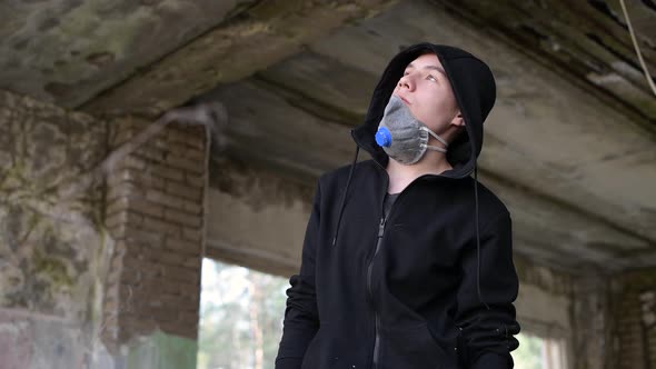A teenager looks into the distance, puts on a respirator and leaves