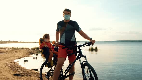 Man with a Child on a Bicycle in Protective Masks