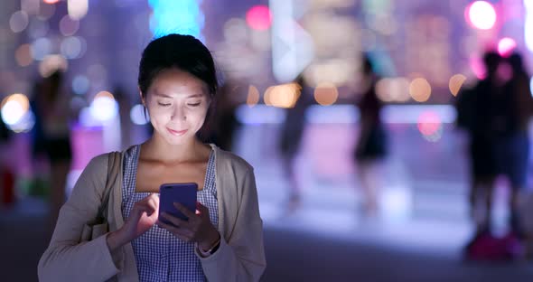 Woman use of mobile phone in city at night