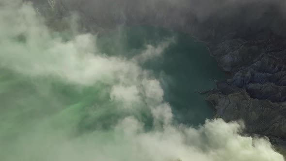 Aerial Pan Down of Acidic Lake With Smoke Inside a Volcano