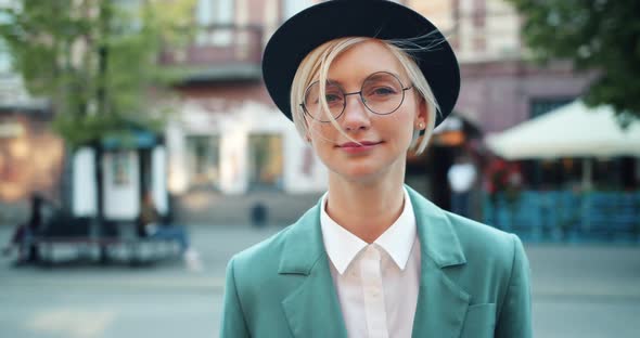 Portrait of Attractive Student Blonde in Hat and Glasses Smiling Outdoors