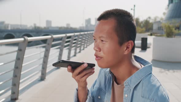 Young Asian Man Recording Voice Message on Cellphone