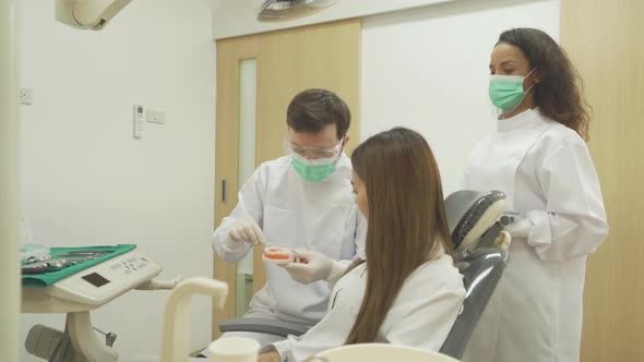 A caucasian dentist man, people showing how to use dental floss with typodont teeth model