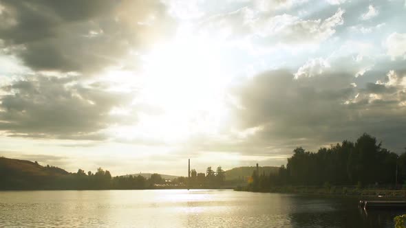 The sun's rays breaking through the grey clouds and illuminate the city pond.