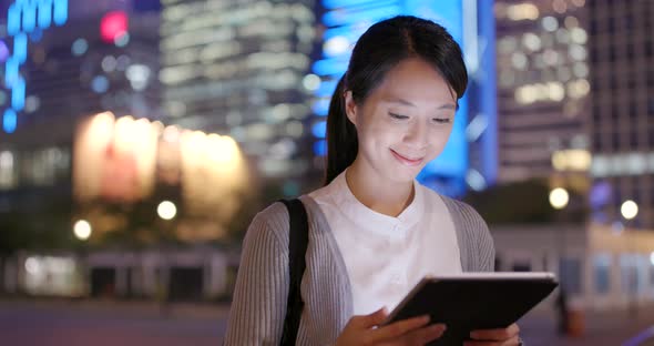 Business Woman Reading on Tablet Computer in City at Night