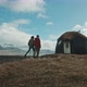 Couple walking to their home above a seaside valley with mountains as a backdrop - VideoHive Item for Sale