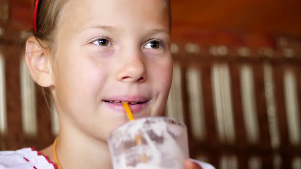 Happy Smiling Teen Girl Child Drinks a Milkshake in Cafe