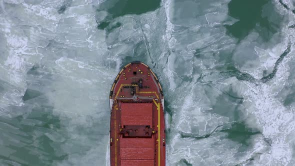 Aerial Above Epic Huge Steel Ship Breaks Ice By Bow of Ship and Floats in Large Sea Ice Floes