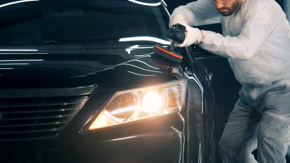 Person Uses Polishing Equipment While Working in a Car Service