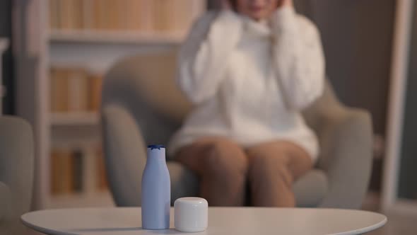 Closeup Cosmetic Products on Table with Blurred Senior Woman Sitting at Background