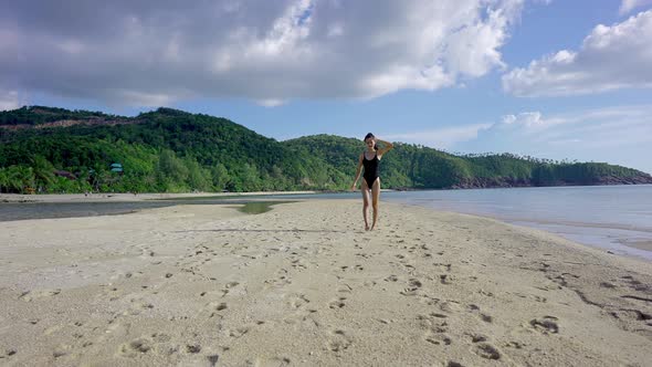 Smiling Pretty Asian Woman in Black Swimsuit Walking Alone on SandbarThailand