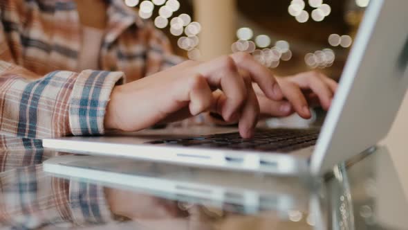 Close-up Woman's Hands Working with Laptop on the Desktop. Girl Blogger Freelancer Works in a Cafe