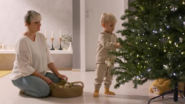 Mother and Toddler Son Celebrating Winter Holidays Decorating the Christmas Tree at Home, Copy Space