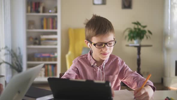 Cute Schoolboy is Doing Homework at Table with Tablet During Quarantine at Home Spbd