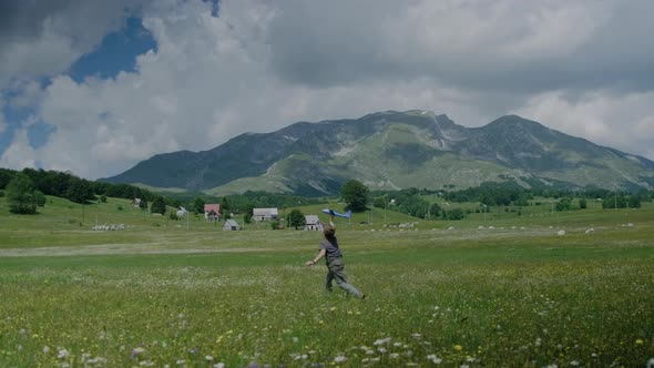 Cute boy kid with a toy blue plane runs through a meadow with flowers