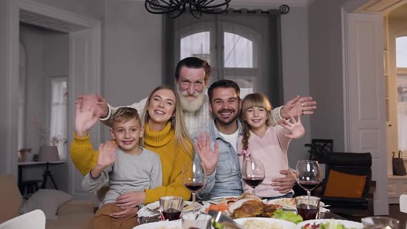 People-Relatives Sitting at the Festive Table and Looking at Camera with Waving Hands