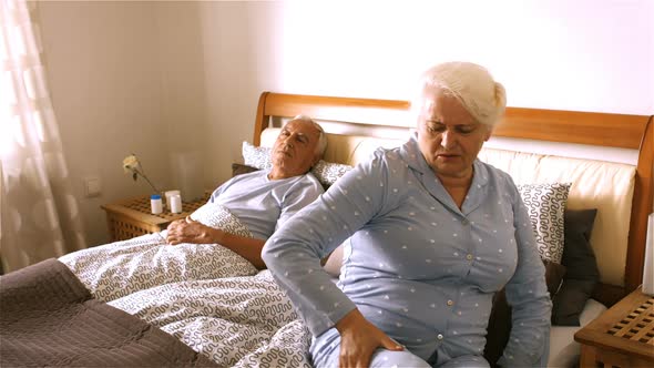 Senior woman suffering from backache sitting on bed